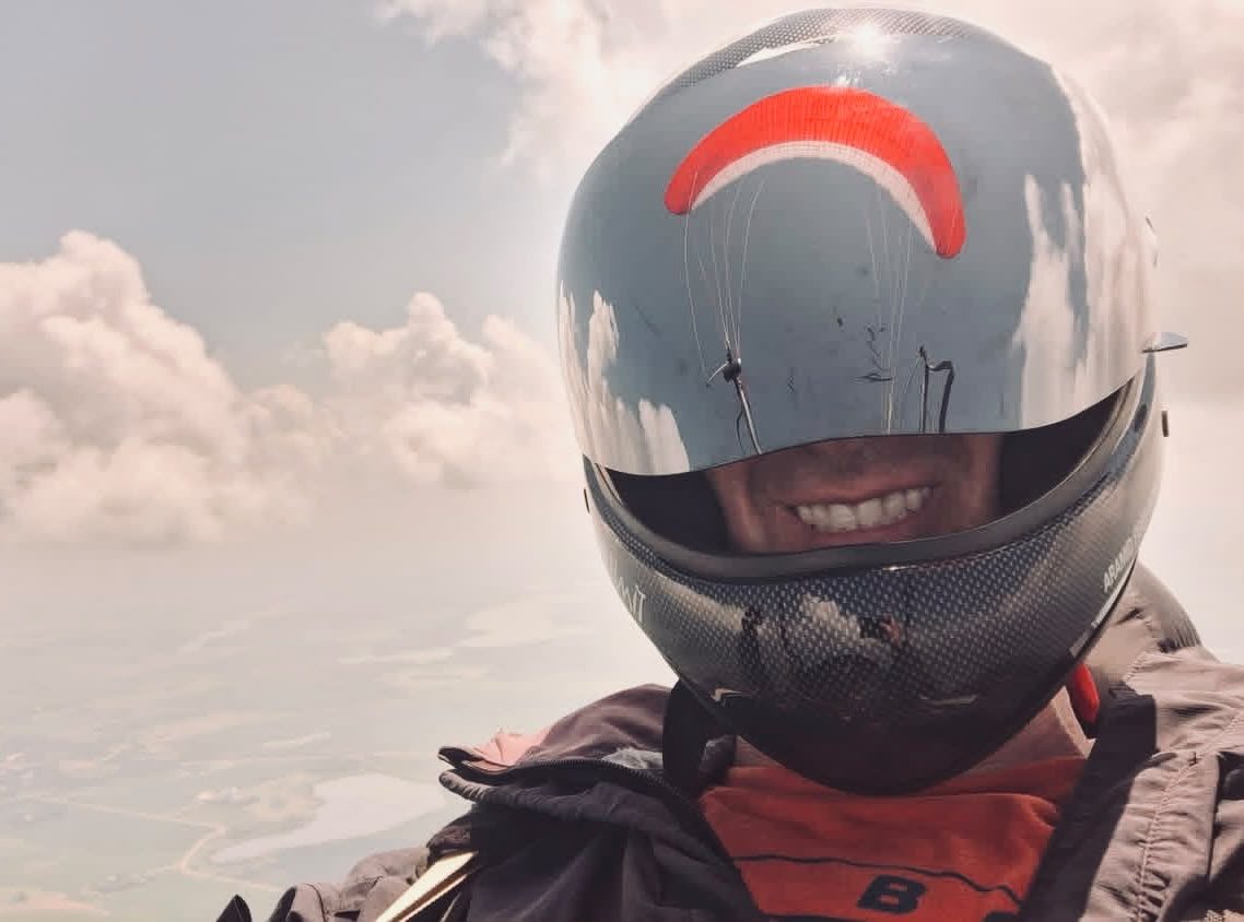 A pilot wing reflected in his helmet visor at altitude